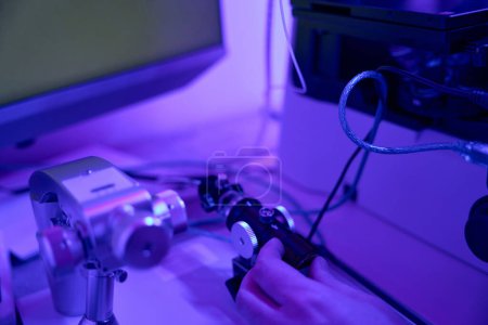 Téléchargez les photos : Travailleur de laboratoire masculin contrôlant le joystick du micromanipulateur et regardant le microscope, faisant un travail micro-précis - en image libre de droit