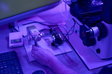 Foto de Biotécnico ajustando micromanipuladores en microscopio antes de trabajar con células biopsia, cultivo o fertilización, laboratorio de reproducción - Imagen libre de derechos