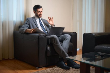 Foto de Hombre de negocios de mediana edad trabaja con documentos en la zona de relax, utiliza un ordenador portátil - Imagen libre de derechos