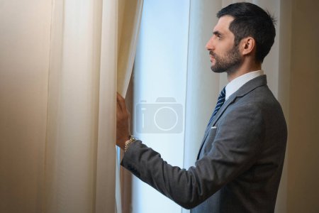 Foto de Huéspedes de hotel de mediana edad se para en la ventana, macho admira la vista - Imagen libre de derechos