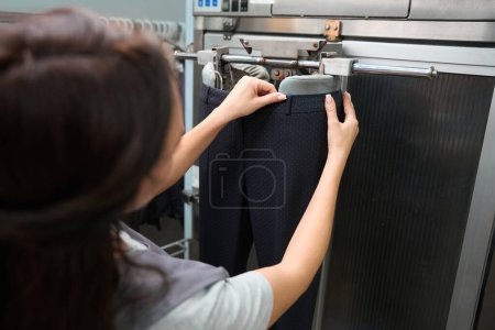 Photo for Lady laundry service worker wearing pants on ironing mannequin and relaxing small wrinkles before ironing, professional facilities - Royalty Free Image
