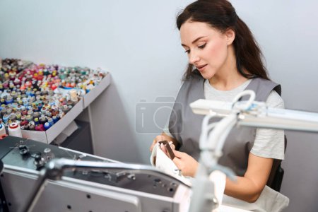 Foto de Alcantarilla femenina inspeccionando pantalones y arrancando etiquetas, preparando ropa para la limpieza en seco, servicio de lavandería profesional - Imagen libre de derechos