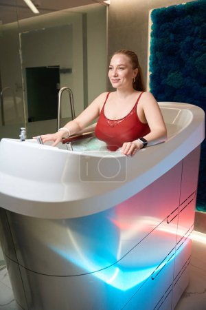 Photo for Client of clinic enjoys a wellness treatment on a aquabike, a decorative panel indoors - Royalty Free Image