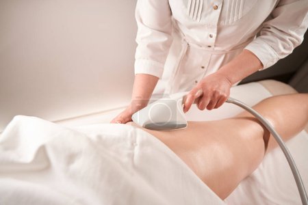 Téléchargez les photos : Masseur spécialiste fait un massage des pieds matériel pour un client, le personnel utilise un équipement moderne - en image libre de droit