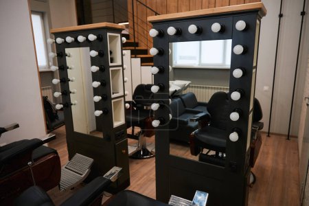 Foto de Elegante lugar de trabajo de peluquería en una barbería con un diseño minimalista moderno, espejos, sillas de cuero, excelente iluminación - Imagen libre de derechos