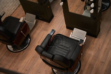 Téléchargez les photos : Chaises confortables dans un salon de coiffure avec un intérieur minimaliste, miroirs, excellent éclairage - en image libre de droit