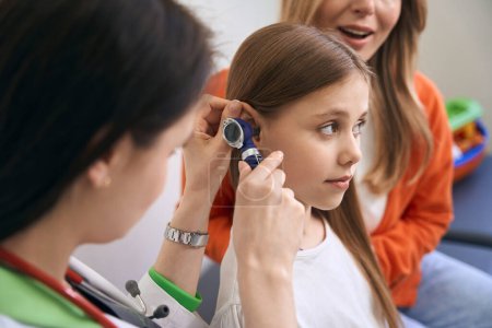 Photo for Ear, nose and throat specialist checking condition of the tympanic septum of little girl complaining on ear pain, qualified medical exam - Royalty Free Image