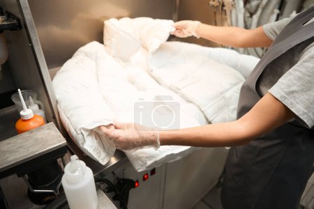 Téléchargez les photos : Femme de bureau de nettoyage à sec inspectant veste de tissu délicat sur la présence de taches, pré et post traitement, service de nettoyage à sec - en image libre de droit