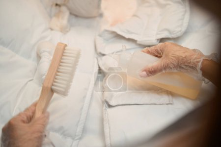 Photo for Close-up female hands in protective gloves applying solvent on dirt at jacket, pre and post-spot treatment of clothes - Royalty Free Image