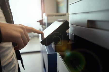 Téléchargez les photos : Employé utilise un photocopieur dans un espace de coworking, équipement de bureau moderne à l'intérieur - en image libre de droit