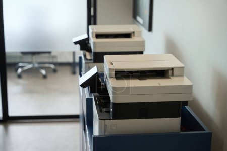 Foto de Dos fotocopiadoras están en la sala de fotocopias de un espacio de coworking, estos son equipos de oficina modernos - Imagen libre de derechos