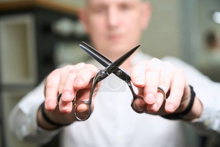 Photo for Barber man holds special professional scissors in his hands, the master has a smart watch - Royalty Free Image