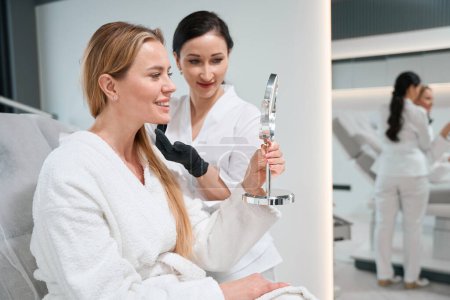 Mujer examina su cara en el espejo después de someterse a procedimientos antienvejecimiento