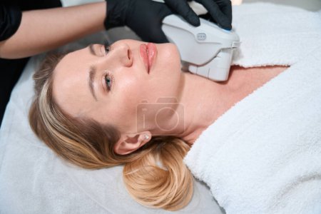 Foto de Paciente cuida la piel de la cara en la clínica de medicina estética, se somete a un procedimiento de hardware para el endurecimiento de la piel - Imagen libre de derechos