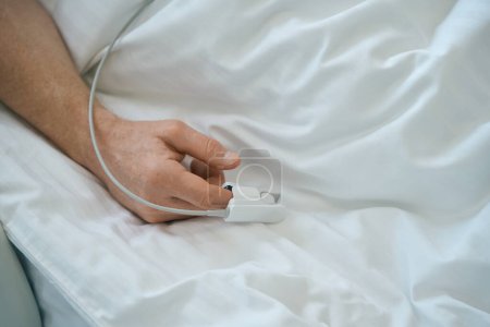 Foto de Primer plano de la mano de los pacientes con oxímetro de pulso en el dedo para medir el oxígeno en el hospital moderno - Imagen libre de derechos