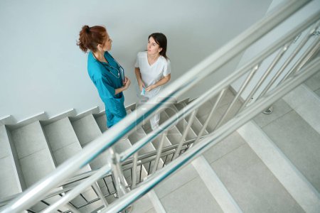 Foto de Especialistas en salud parados en las escaleras y hablando de momentos de trabajo en el hospital - Imagen libre de derechos