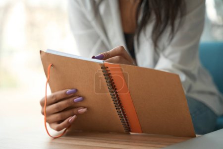 Photo for Cropped view of female with beautiful manicure holding and reviewing notebook indoors - Royalty Free Image