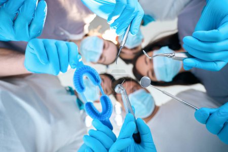 Photo for Men and women with dental instruments in their hands, people in medical uniforms and protective gloves - Royalty Free Image