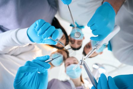 Foto de Cinco dentistas con herramientas especiales en sus manos, personas con uniformes médicos y guantes protectores - Imagen libre de derechos