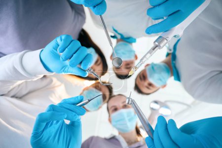 Photo for Team of young dentists with special tools in their hands, people in medical uniforms - Royalty Free Image