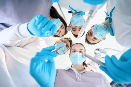 Equipo de jóvenes dentistas con instrumentos dentales en sus manos, personas con uniformes médicos