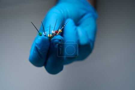 Foto de Hombre demuestra agujas especiales para la limpieza de canales dentales, un dentista en guantes de protección - Imagen libre de derechos