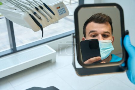 Téléchargez les photos : Médecin dans le cabinet dentaire sur le lieu de travail prend un selfie, le panneau de commande et les buses de l'appareil dentaire - en image libre de droit