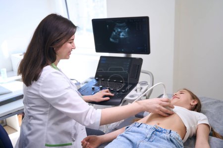 Foto de Mujer realiza una ecografía de los órganos internos de una niña, el médico se comunica amablemente con una paciente joven - Imagen libre de derechos