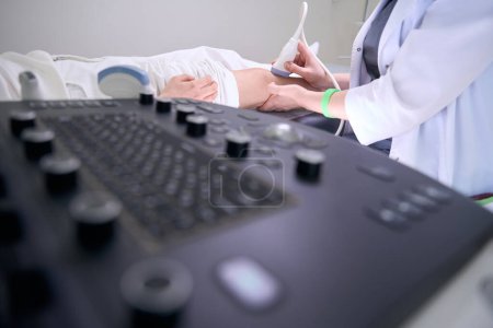 Foto de Diagnóstico utiliza equipos modernos para el ultrasonido de la articulación de la rodilla, el paciente se encuentra en un sofá médico - Imagen libre de derechos