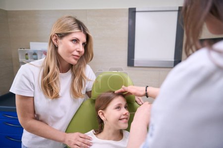 Photo for Specialist otolaryngologist examines the nose of a small patient, next to her mother supports the child - Royalty Free Image