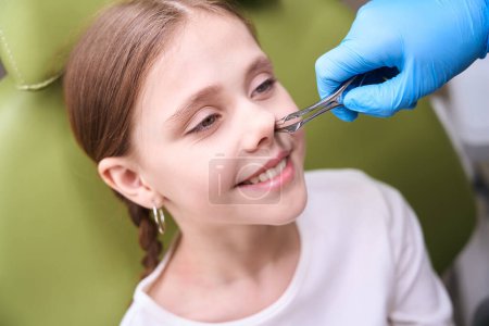 Photo for Doctor otolaryngologist in protective gloves examines the childs nose, the doctor uses special tools - Royalty Free Image