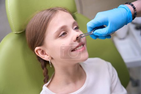 Téléchargez les photos : Spécialiste otolaryngologue en gants de protection examine le nez des enfants, le médecin utilise des outils spéciaux - en image libre de droit