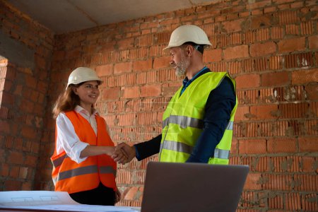 Photo for Satisfied with qualitative blueprint foreman shaking hand to female architect in hardhat, meeting on construction site - Royalty Free Image