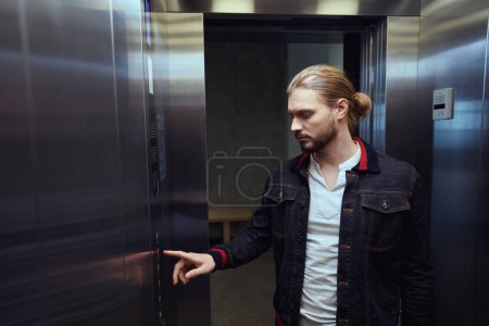 Photo for Man is in the cabin of a passenger elevator, he presses a button on the panel - Royalty Free Image