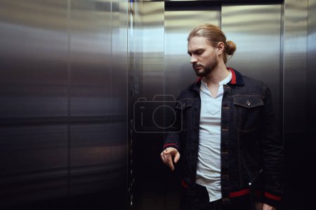 Photo for Male stands in the cabin of a passenger elevator, he presses a button on the panel - Royalty Free Image