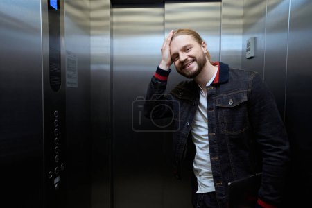 Téléchargez les photos : Le type vêtu d'une veste en jean est dans l'ascenseur, à droite se trouve un panneau avec des boutons de sélection au sol - en image libre de droit