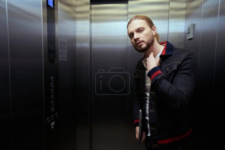 Téléchargez les photos : Le type avec l'ordinateur portable est dans l'ascenseur, à droite est un panneau avec des boutons de sélection de plancher - en image libre de droit