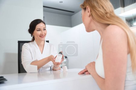Photo for Brunette esthetician offers a blonde woman an effective skin care product, she selects options for non-surgical skin tightening - Royalty Free Image