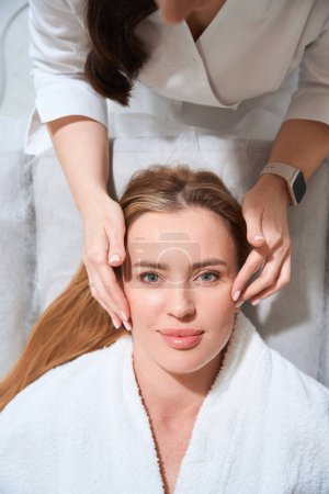 Téléchargez les photos : Femme sur le lieu de travail fait un massage professionnel à un patient, un spécialiste travaille avec un visage de femme - en image libre de droit