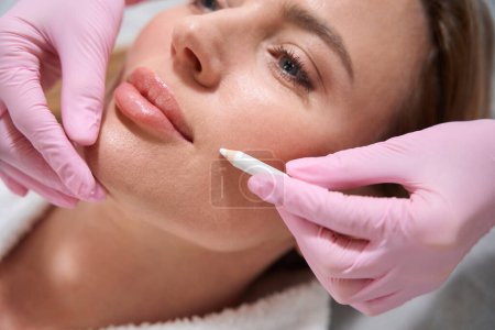 Photo for Blonde female on a consultation in a cosmetology clinic, a specialist uses a special marker - Royalty Free Image