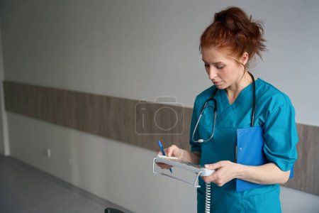Téléchargez les photos : Infirmière avec stéthoscope personnalisant le panneau de commande du superviseur à distance du lit réglable électriquement dans la chambre d'hôpital - en image libre de droit