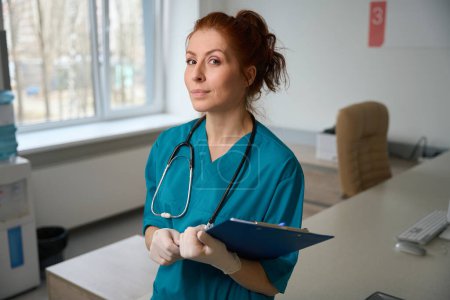 Photo for Portrait of confident female medic attiring doctor uniform and holding clipboard with patient analysis in hospital - Royalty Free Image