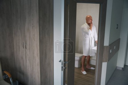 Photo for Full-length portrait of mature male patient in bathrobe standing in bathroom of hospital ward - Royalty Free Image