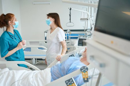 Photo for The proficient physicians talking with each other near patients bed in the resuscitation chamber - Royalty Free Image