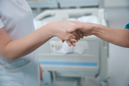 Photo for Close up of female physicians shaking hands to each other at clinic - Royalty Free Image