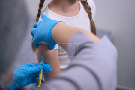 Photo for Child receives a vaccination in the clinic, the doctor uses a thin needle - Royalty Free Image