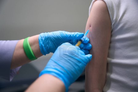 Foto de Paciente en la clínica recibe una inyección en el brazo, el médico utiliza una aguja delgada - Imagen libre de derechos