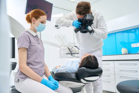 Foto de Estomatólogo usando cámara de rayos X dental para recibir imagen de los dientes del cliente, para ver la calidad de las raíces y los nervios, servicio de clínica privada - Imagen libre de derechos