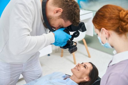 Photo for Attractive woman smiling showing all her teeth to dental technician make x-ray image og her oral cavity on portable dental camera, nurse assistant to doctor - Royalty Free Image