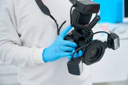 Photo for Doctor in uniform and protective gloves holding and showing portable x-ray camera, important device in stomatological practice - Royalty Free Image